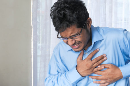 young man suffering pain in heart and holding chest with hand