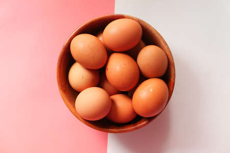 Top view of eggs in a bowl on color backgroundの写真素材