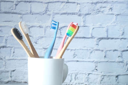 colorful toothbrushes in white mug against a wallの写真素材