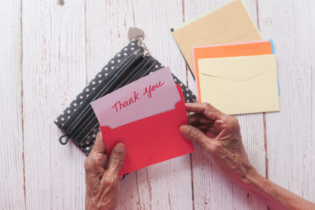 senior womens hand holding thank you note , top down