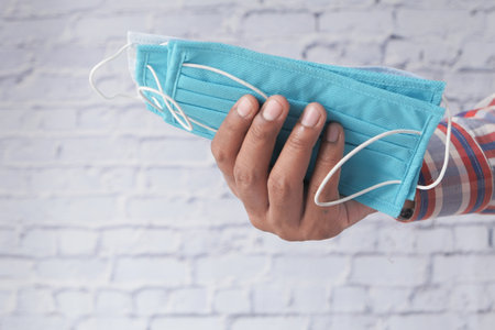 man hand holding surgical face mask, close upの写真素材