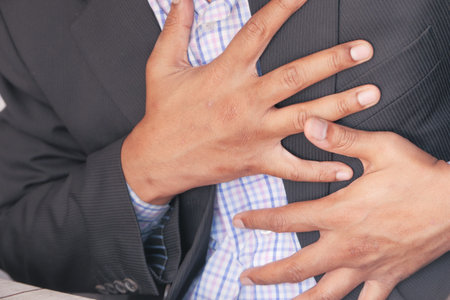 young man suffering pain in heart and holding chest with hand