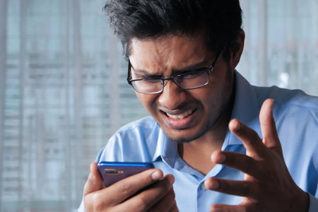 upset man reading bad news on smart phoneの写真素材