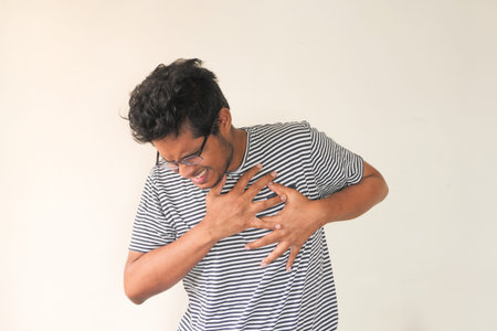 young man suffering pain in heart and holding chest with hand