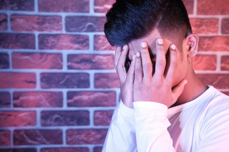Close up of sad man covering face with hand.