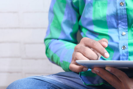 man sitting on floor using digital tablet at home