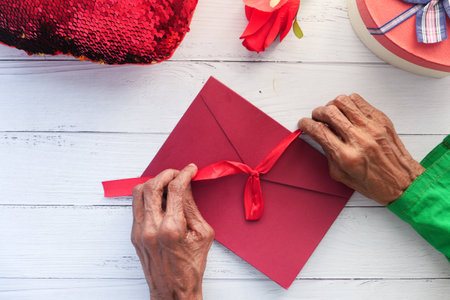 senior women hand on red color envelope and gift on tableの写真素材