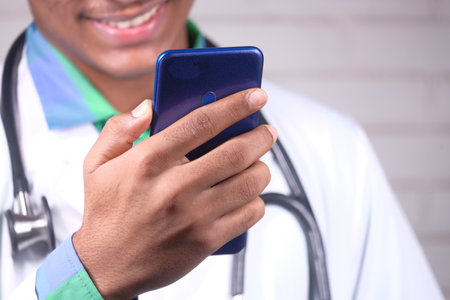doctor in white coat using a smartphone for video conferenceの写真素材