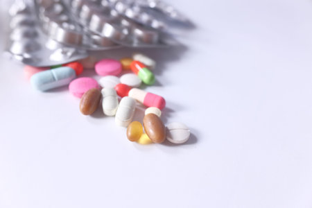 Close up of many colorful pills and capsules spilling on white