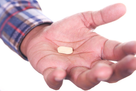 Close up of man hand holding pills isolated on whiteの写真素材