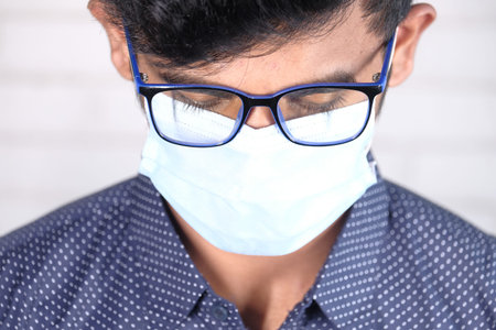 A young man with protective mask against a wall