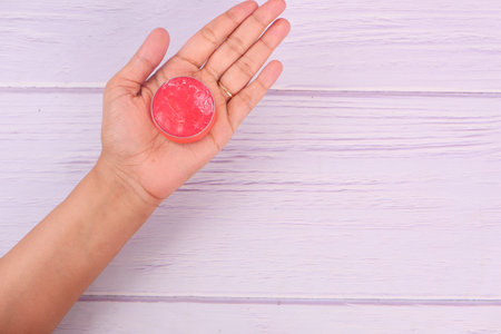 woman using petroleum jelly onto skin at home close up.