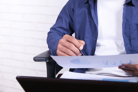 young man sitting on a chair analyzing financial data on paper