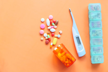 digital thermometer , pill box and pills on orange backgroundの写真素材