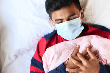 top view of sick men with surgical face mask on bed putting hand on chest