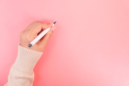 women hand writing with pen on pink backgroundの写真素材