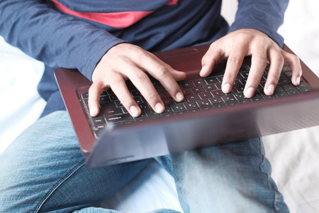 Work from home concept, unrecognized man sitting on bed typing on laptopの写真素材