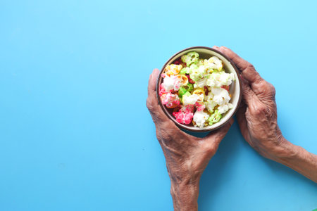 top view of senior women hand holding a bowl of colorful popcornの写真素材