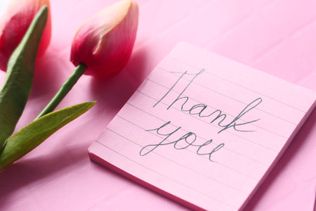 thank you message on sticky note with tulip flower on pink background