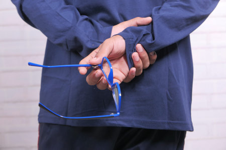 Close up of man hand holding eyeglass in dark.