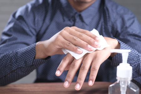 man disinfecting his hands with a wet wipe.の写真素材