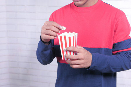 young man eating popcorn close upの写真素材