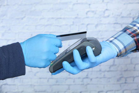 hand in medical gloves contactless payment with credit card