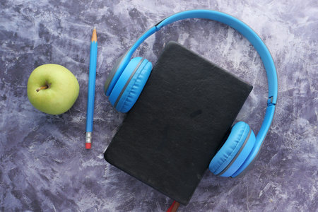 Audio book concept. Headphones and notepad on black background