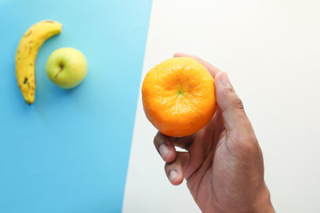 hand holding ripe orange fruit on color backgroundの写真素材