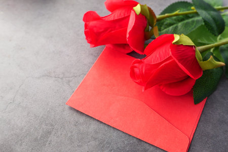 Close up of envelope and rose flower on black backgroundの写真素材