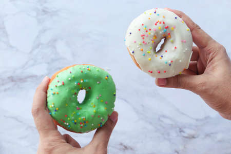 women hand holding fresh donuts close upの写真素材