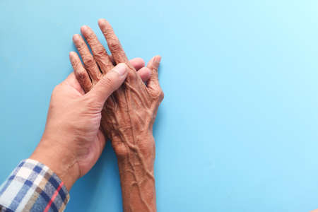 man holding hand of a senior women on blue backgroundの写真素材