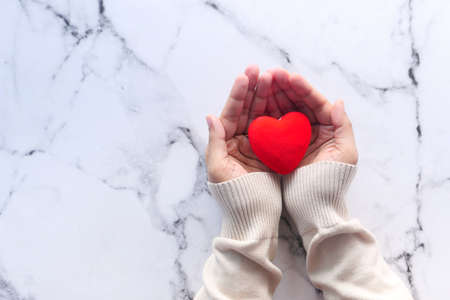 women holding red heart on tiles background , top viewの写真素材