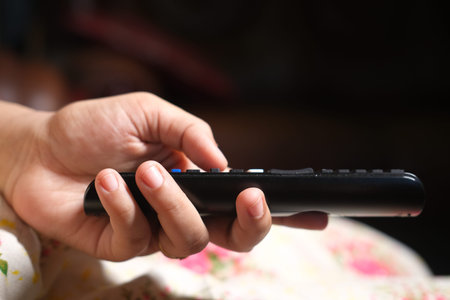close up of women hand holding tv remote.の写真素材