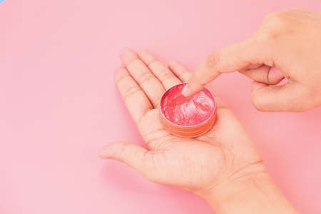 woman using petroleum jelly on pink backgroundの写真素材