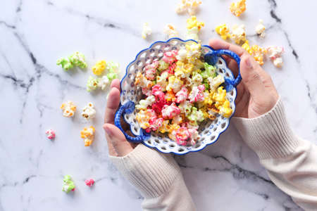 top view of women hand holding a bowl of colorful popcornの写真素材