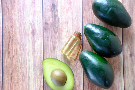 Top view of oil and slice of avocado on wooden table