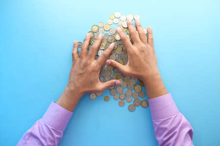 top view of man hand counting coins on color backgroundの写真素材