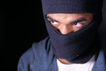 Thief in a mask on black background close up,