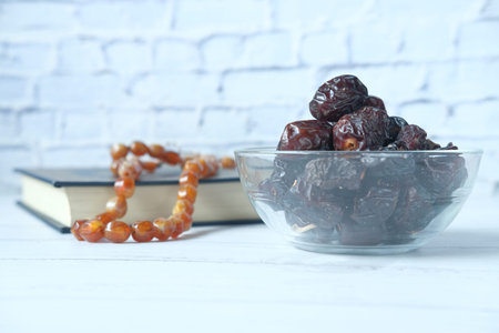 fresh date fruit in a bowl and holy book of quran on table