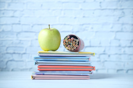 colorful books , apple and color pencil on table