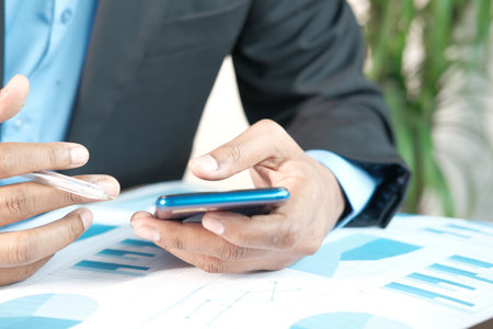 businessman using smart phone while working on deskの写真素材