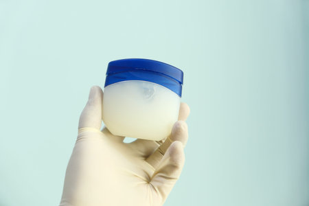 hand in latex gloves holding petroleum jelly