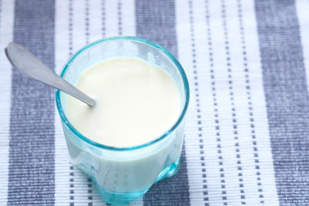 Close up of glass of milk and spoon on tableの写真素材