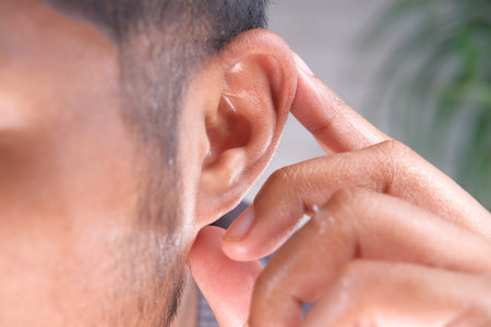 close up of young man holding ear suffering pain