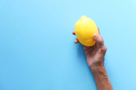 senior women holding lemon on blue