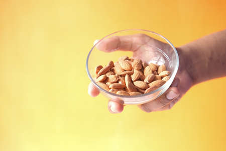 close up person hand holding a bowl on almondの写真素材