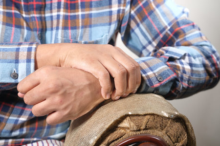man suffering pain in wrist sitting on sofa close up
