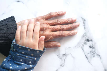 detail shot of child girl holding hand of a senior womenの写真素材