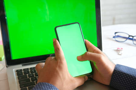 rear view of young man using smart phone and laptop on tableの写真素材